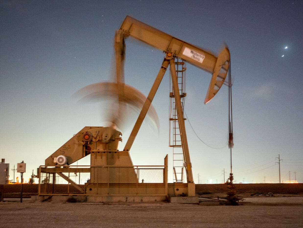 Pumpjack silhouetted against a warm gold dusk sky